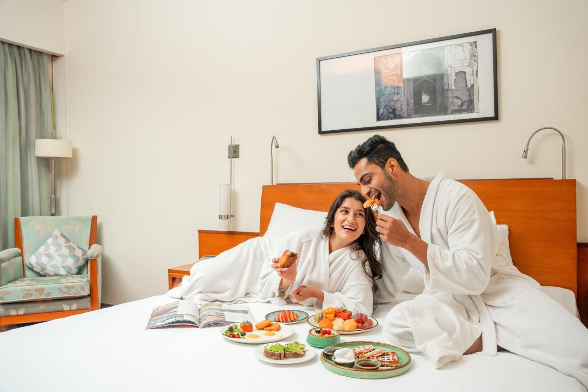Hyatt Pune Extérieur photo A couple eating breakfast in bed